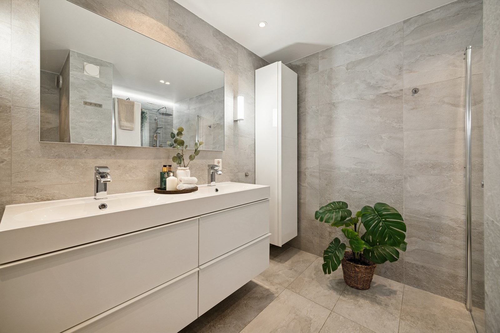 Badet er tidløst og moderne med store fliser og hvit innredning. Galleribilde