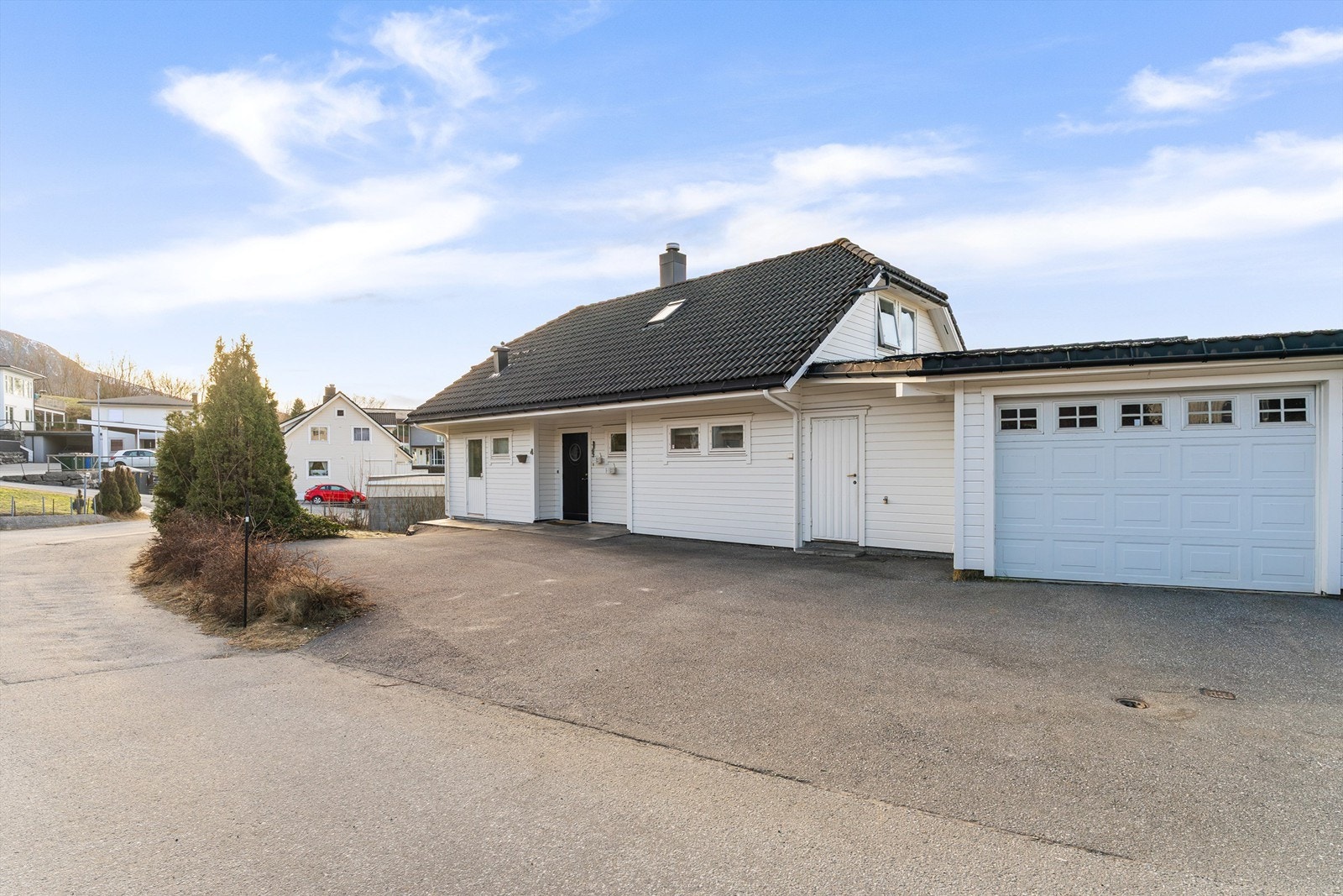 Asfaltert innkjørsel og gårdsplass. Garasje er oppført vegg i vegg med naboeiendommens garasje. Galleribilde