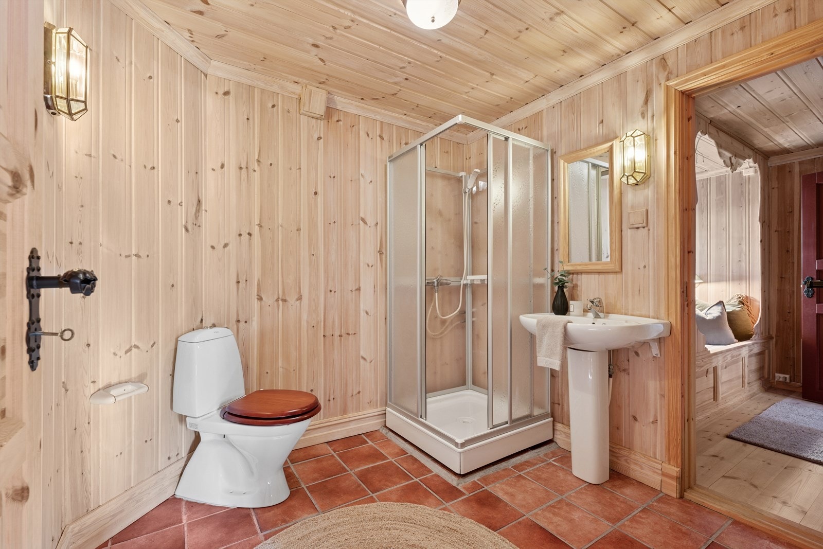 Badet i første etasje har flislagt gulv, trepanel på vegger og i himling. Utstyrt med toalett, servant med søyle og dusjkabinett. Naturlig ventilasjon med ventil i yttervegg Galleribilde