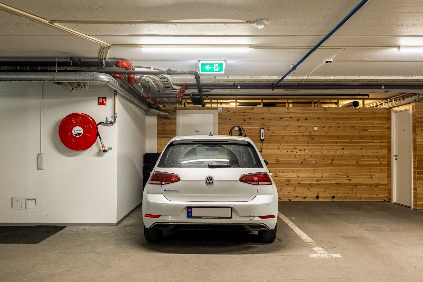 Parkeringsplass i garasje med nyinstallert elbillader, nær heisen og gjesteparkering. Galleribilde