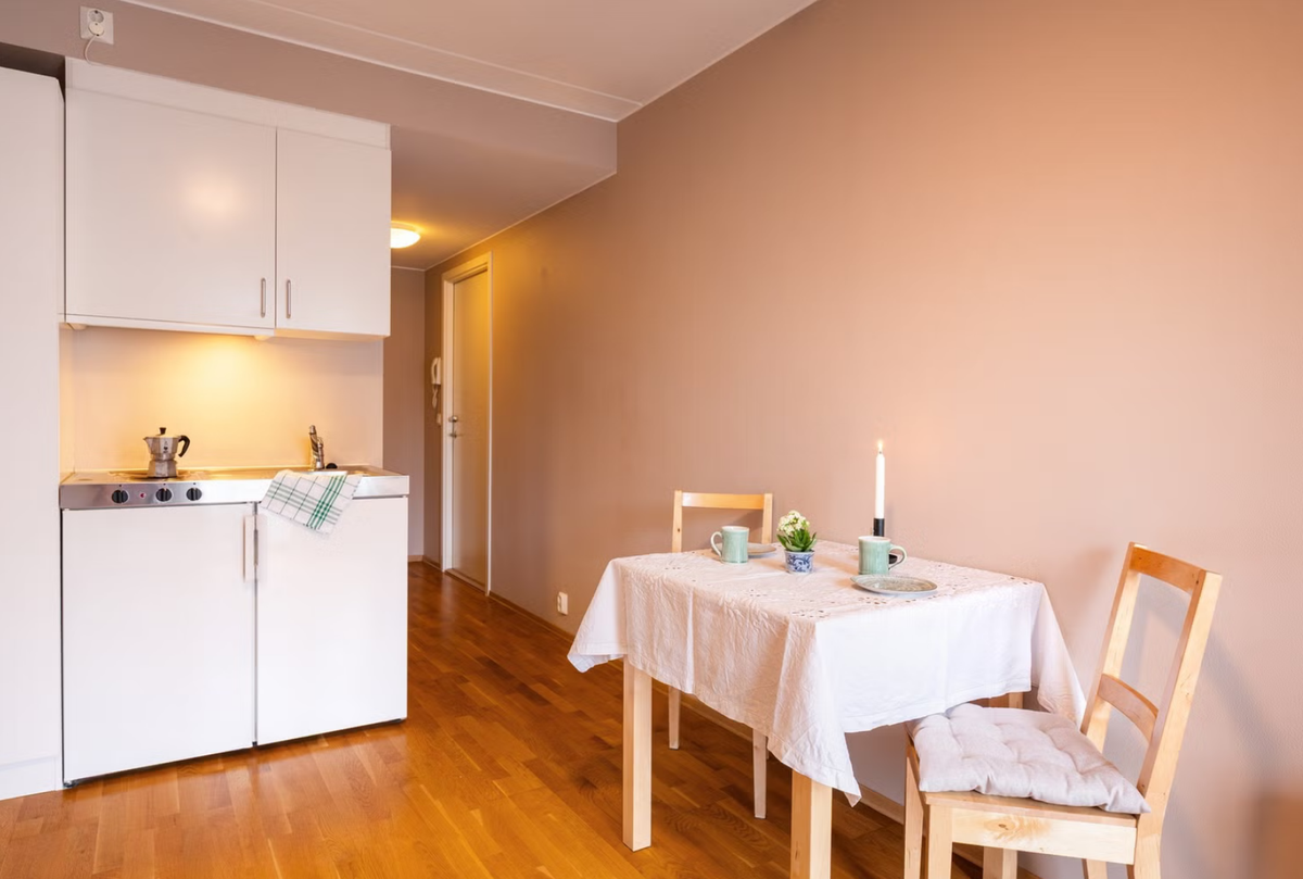 Kjøkkenet har innredning fra byggeår med slette fronter og benkeplate i rustfritt stål med nedfelt oppvaskkum. Galleribilde