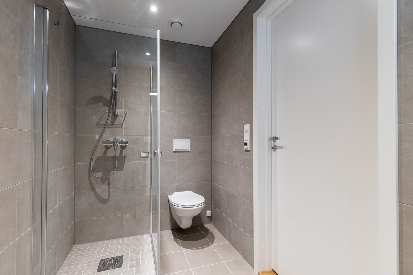 Veggene er kledd med grå fliser i 30x60 cm format, mens gulvet har matchende fliser i 30x30 cm. Galleribilde