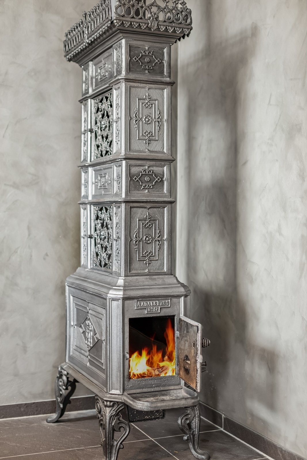 Den detaljerte etasjeovnen er et flott møbel i seg selv og en effektiv varmekilde. Galleribilde