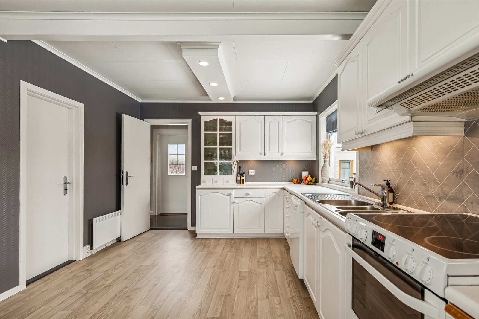 Kjøkkenet har en klassisk innredning med lakkerte fyllingsdører og vitrineskap med sprosser. Galleribilde