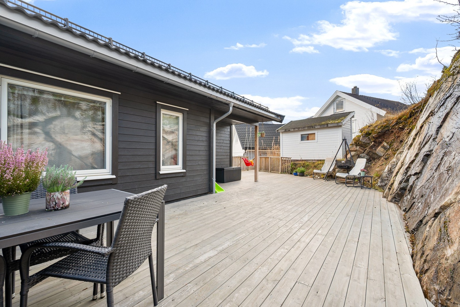 På baksiden er det stort terrasseområde med rikelig plass til utemøblement og grill/bålpanne Galleribilde