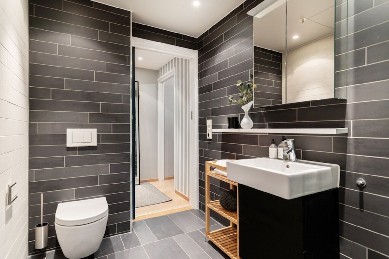 Leiligheten har et delikat bad med en lekker kombinasjon av lyse og mørke fliser. Galleribilde