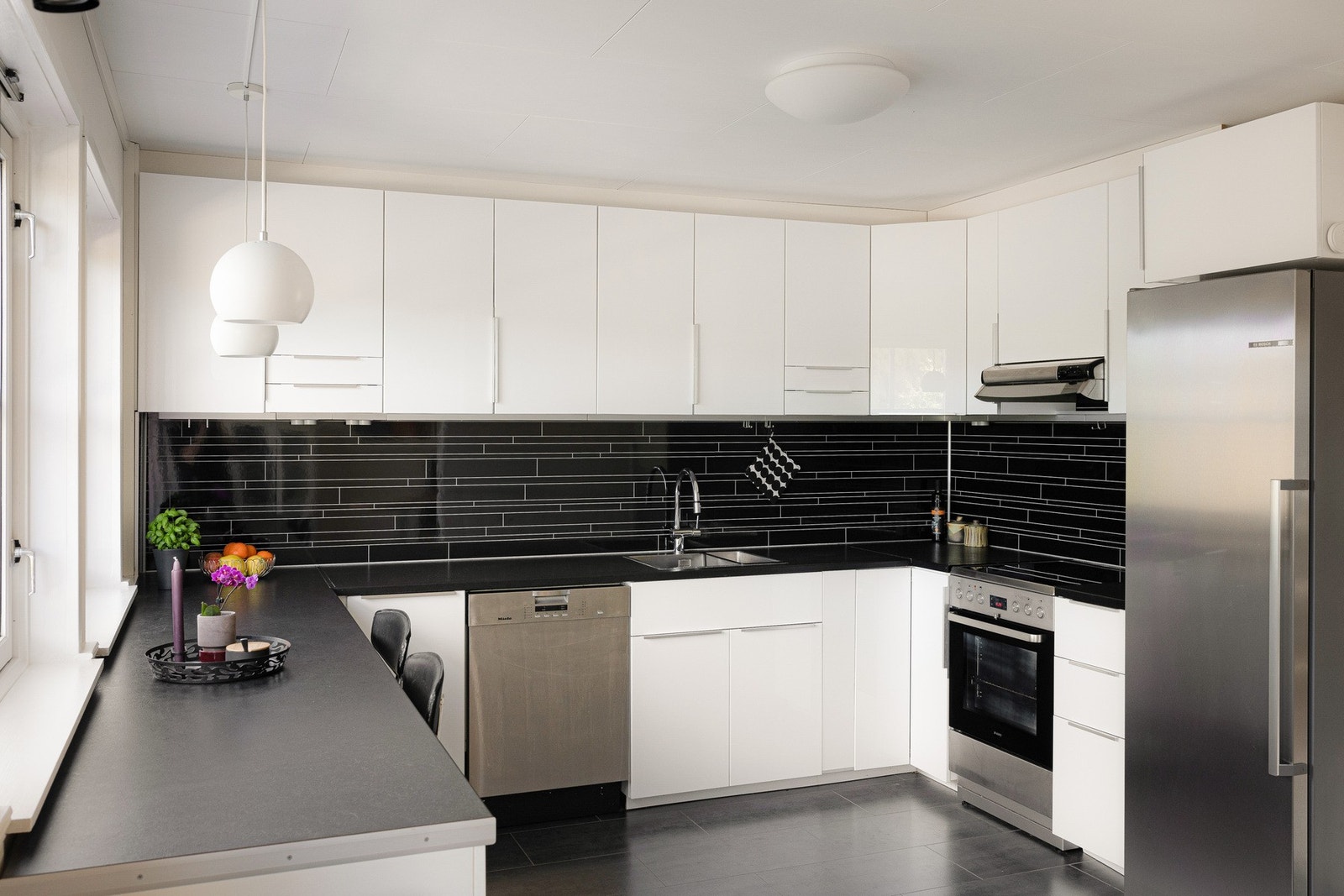 Stort og godt kjøkken, innredning i glatte høyglans skapfronter, laminat benkeplate med sprutplate på bakvegg, oppvaskkum og ventilator. Galleribilde