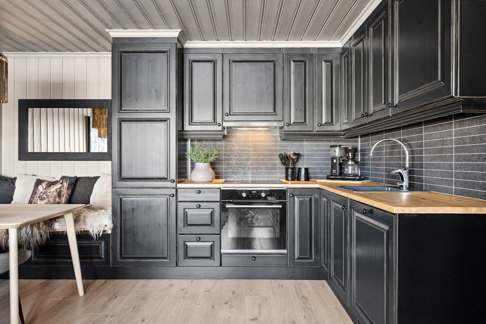 Innredning av lekker og mørk utførelse i heltere, med malt profilerte fronter og heltre benkeplate med oppvaskkum i kompositt. Kjøkkenet er av høy kvalitet, laget av Gudmund Kyrkjebø på Dalen, Kyrkjebø trevare. Galleribilde