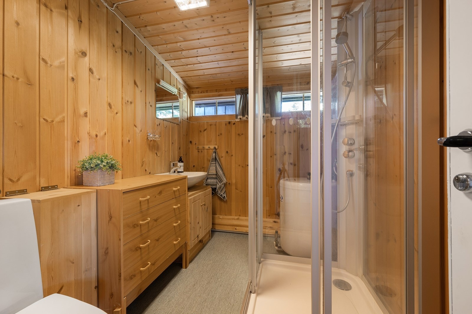 Praktisk bad med dusjkabinett, wc og kommoder for oppbevaring. Galleribilde