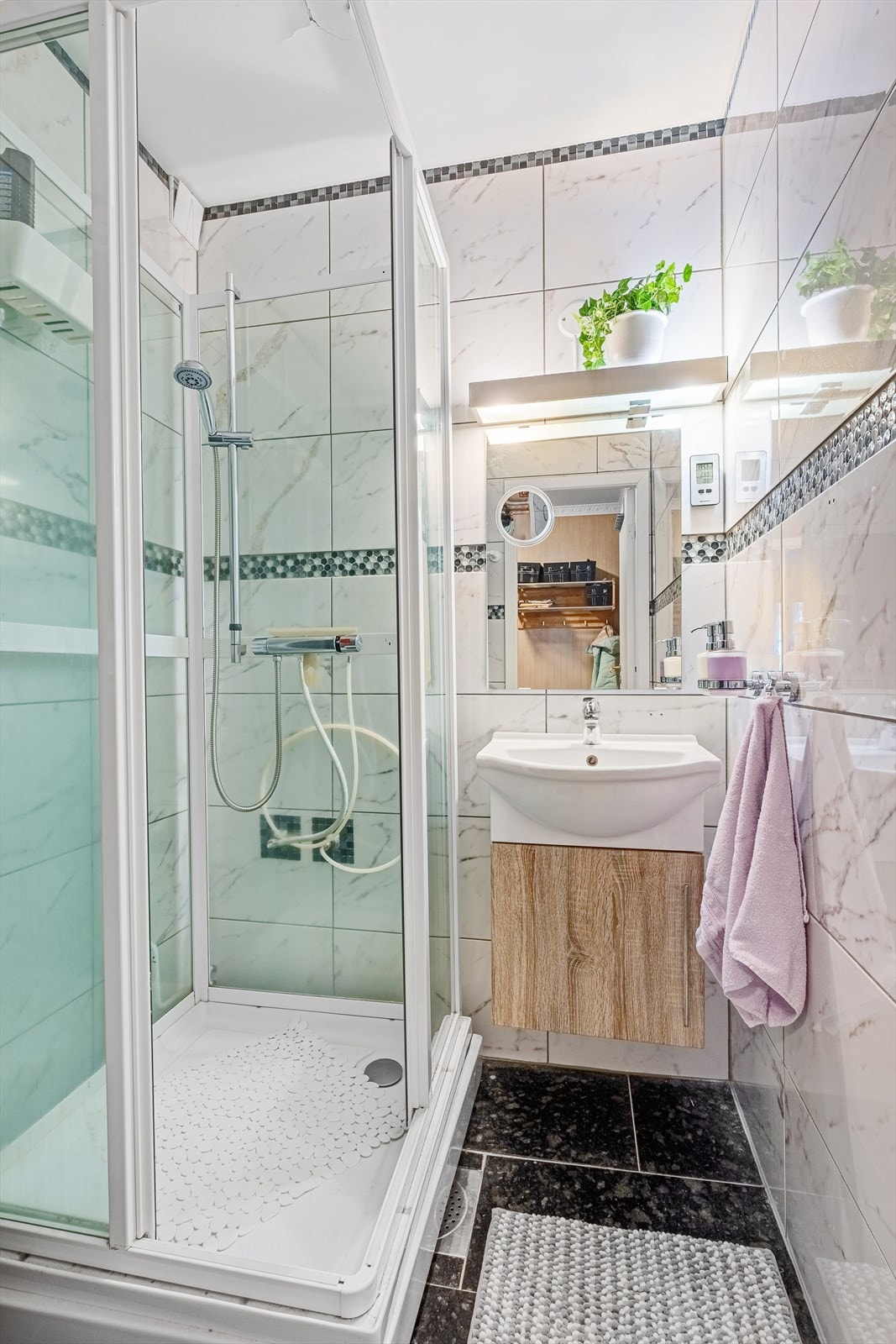 Badet er flislagt og inneholder dusjkabinett og servant med underskap. Galleribilde