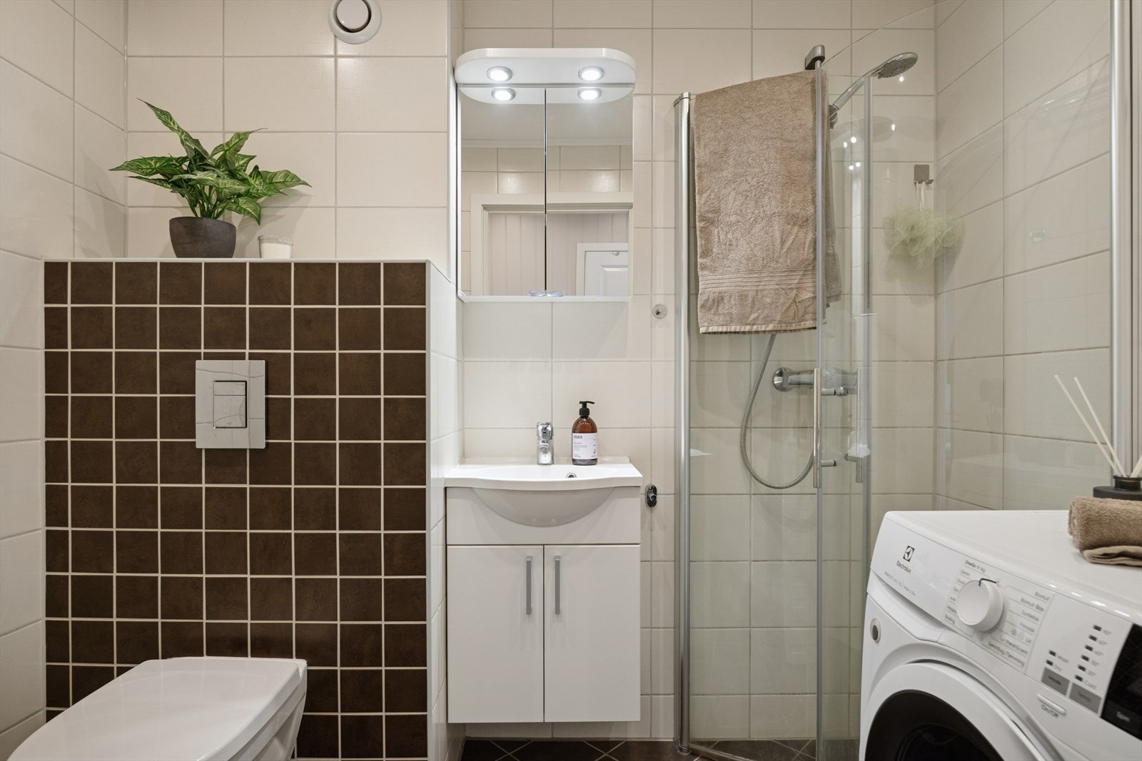 Baderommet innredet med veggmontert toalett, dusjhjørne med innsvingbare dører for maskimal utnyttelse av rommet. Galleribilde