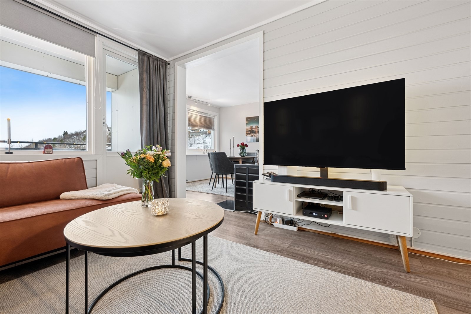 Romslig planløsning med naturlig inndeling av stue med tv-stuedel og spisestuedel Galleribilde