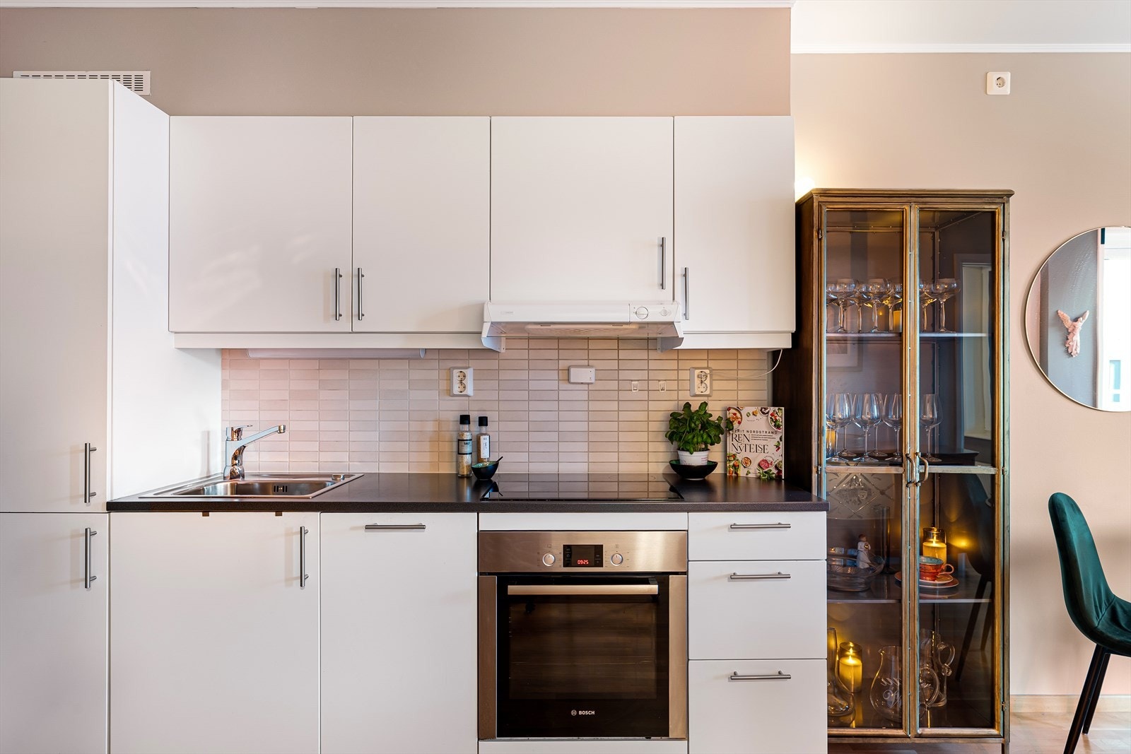 Kjøkkenet fremstår som både funksjonelt og stilrent, godt utnyttet med over- og underskap, flislagt vegg bak benkeplate og integrerte hvitevarer. Galleribilde