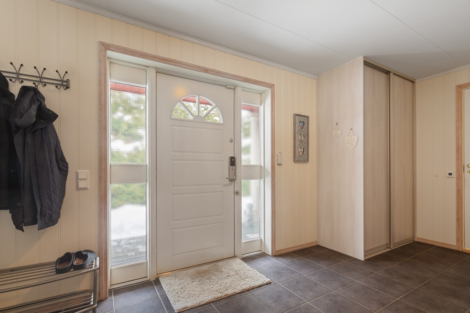 Malt hovedytterdør med sidefelt slipper lys inn i entreen. Galleribilde