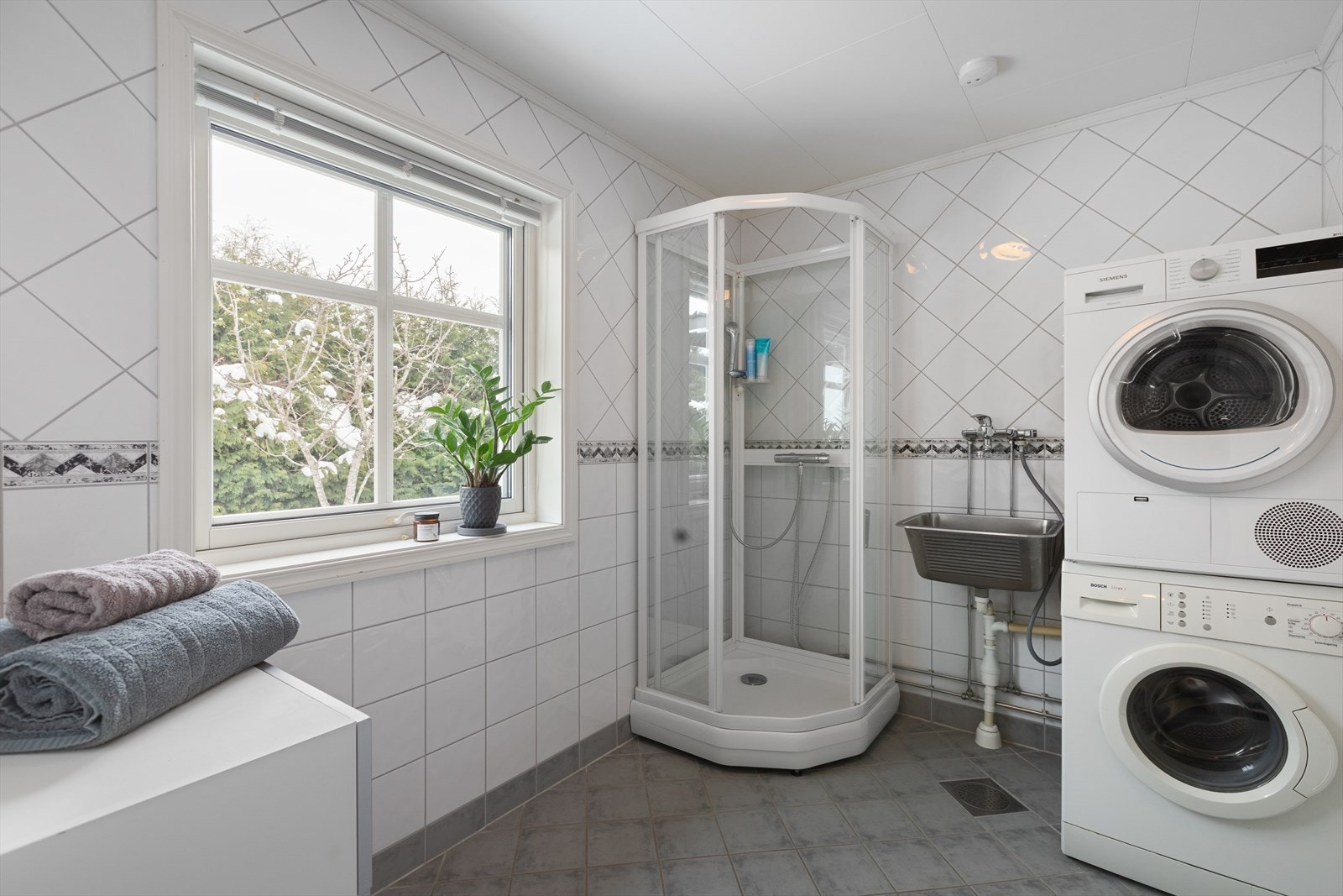 Praktisk bad i første etasje med flislagt gulv, dusjkabinett og opplegg for vaskemaskin. Galleribilde