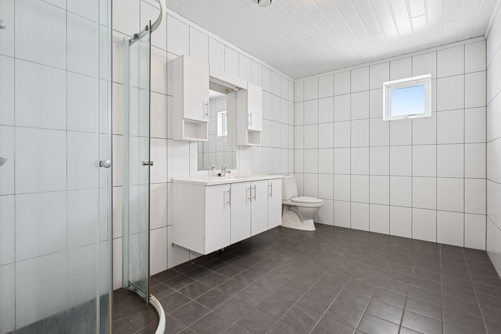 Rommet fremstår delikat og tidløst med dusjhjørne og baderomsinnredning med oppbevaring. Galleribilde