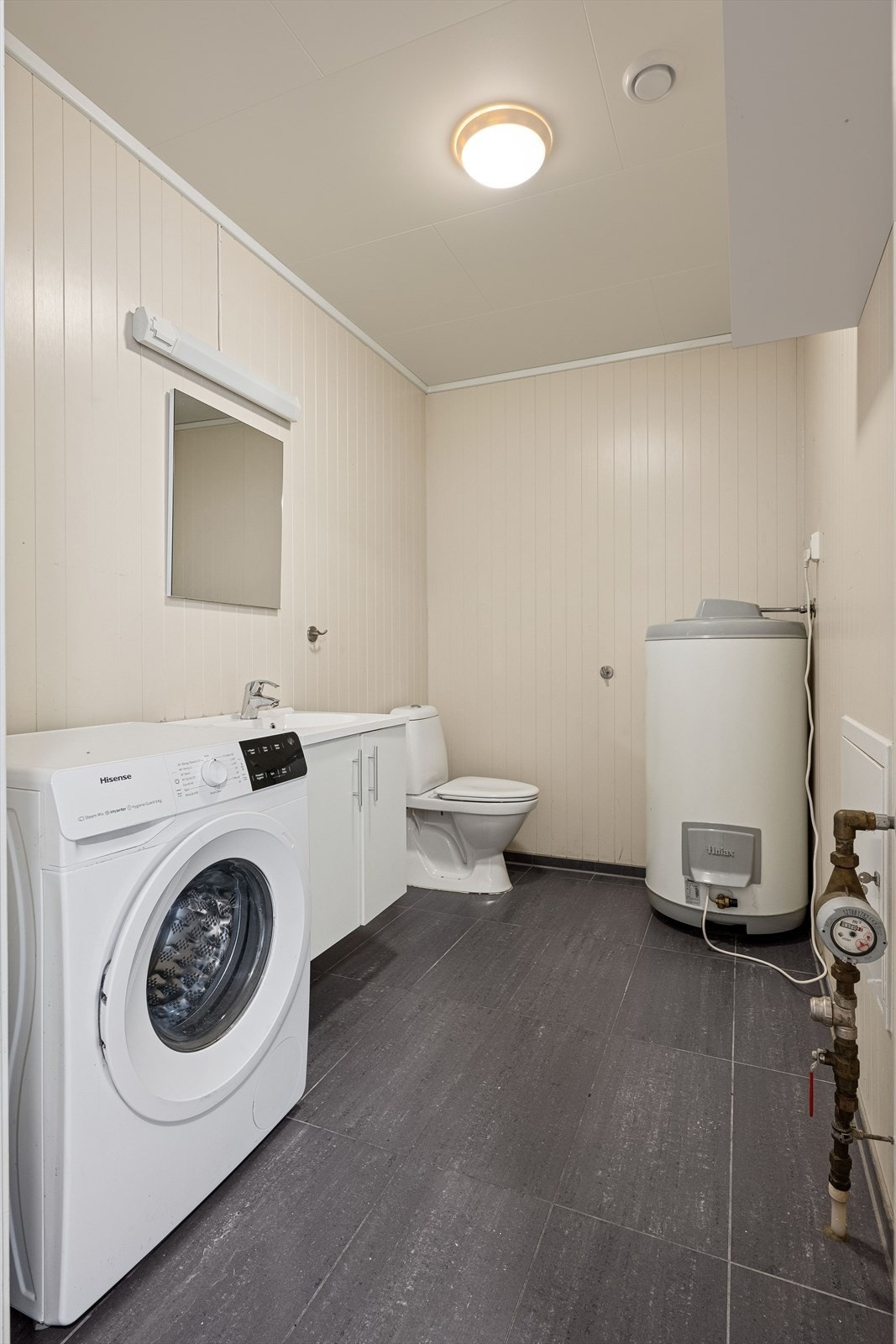 I 1. etasje ligger et toalettrom med opplegg vaskemaskin, rommet har fliser på gulv, panelplater på vegger og himlingsplater. Galleribilde
