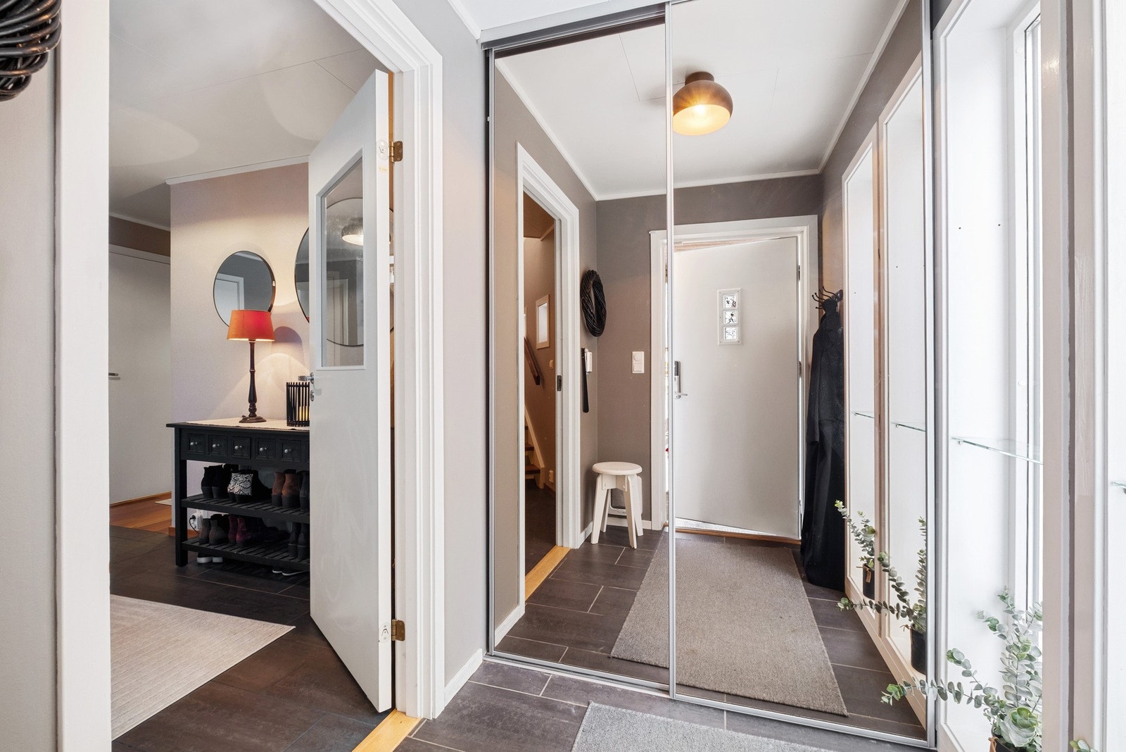 Innbydende entre med flislagt gulv og skyvedørsgarderobe med speilfronter Galleribilde