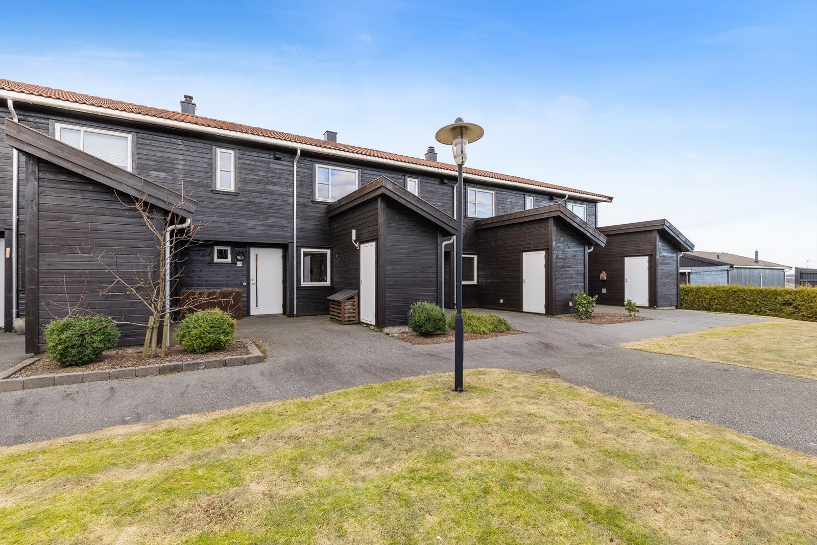 Inngangspartiet er asfaltert og har bed med vintergrønn beplantning som gir et godt førsteinntrykk av boligen. Boligen har også en utvendig bod utstyrt med varmepumpe som gir god lagringsplass. Galleribilde