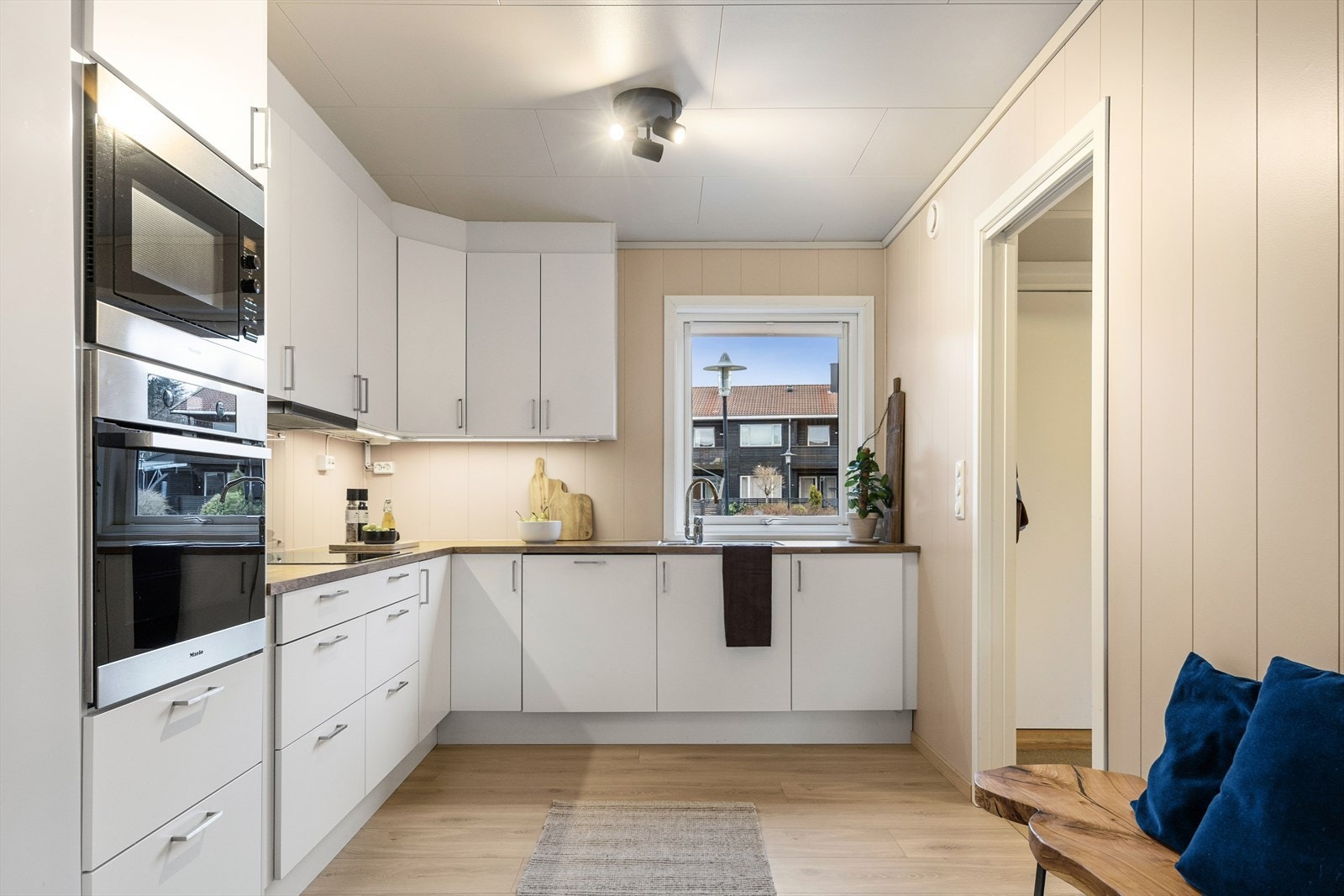 Kjøkkenet er stilrent innredet med hvite, slette fronter og trefarget benkeplate i laminat. Et stort og godt kjøkken hvor man har rikelig med lagringsplass og gode arbeidsflater på benk. Galleribilde