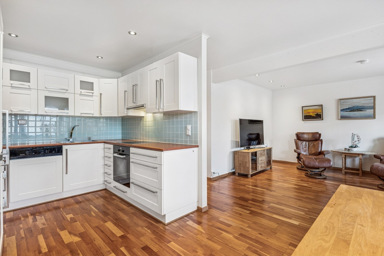 Åpen løsning mellom kjøkken og stue gir en romslig følelse, med parkettgulv som går gjennom begge rom. Galleribilde