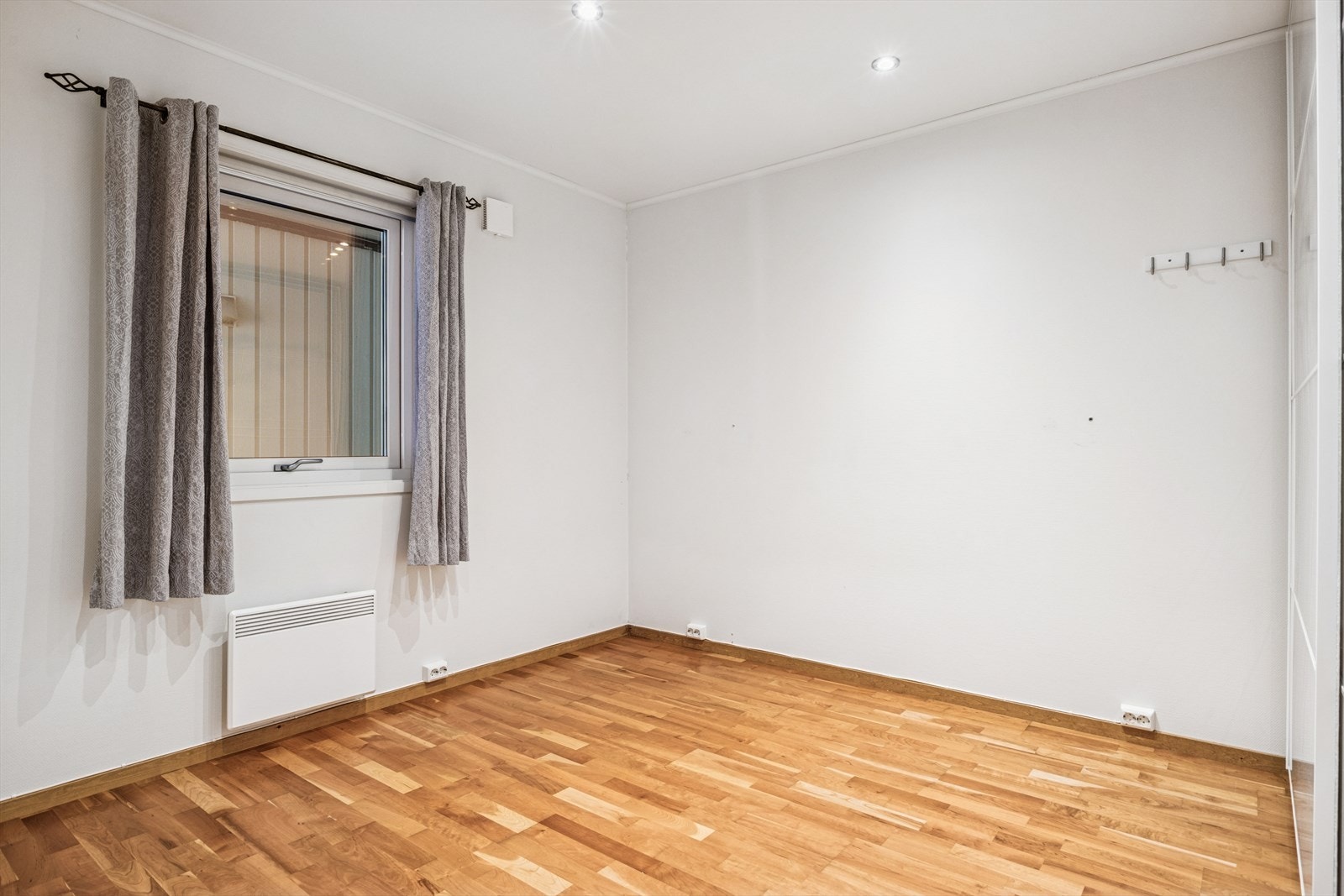 Parkettgulv gir et varmt inntrykk i rommet. Veggene er malt i en lys farge som gir en nøytral bakgrunn. Galleribilde