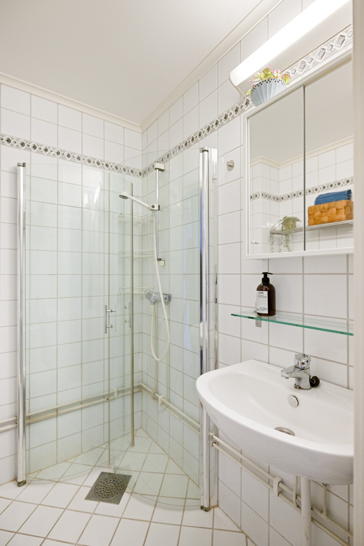 Baderommet er utstyrt med vegghengt servant med speilskap og belysning over, dusjhjørne med innfellbare glassdører og gulvstående toalett. Galleribilde