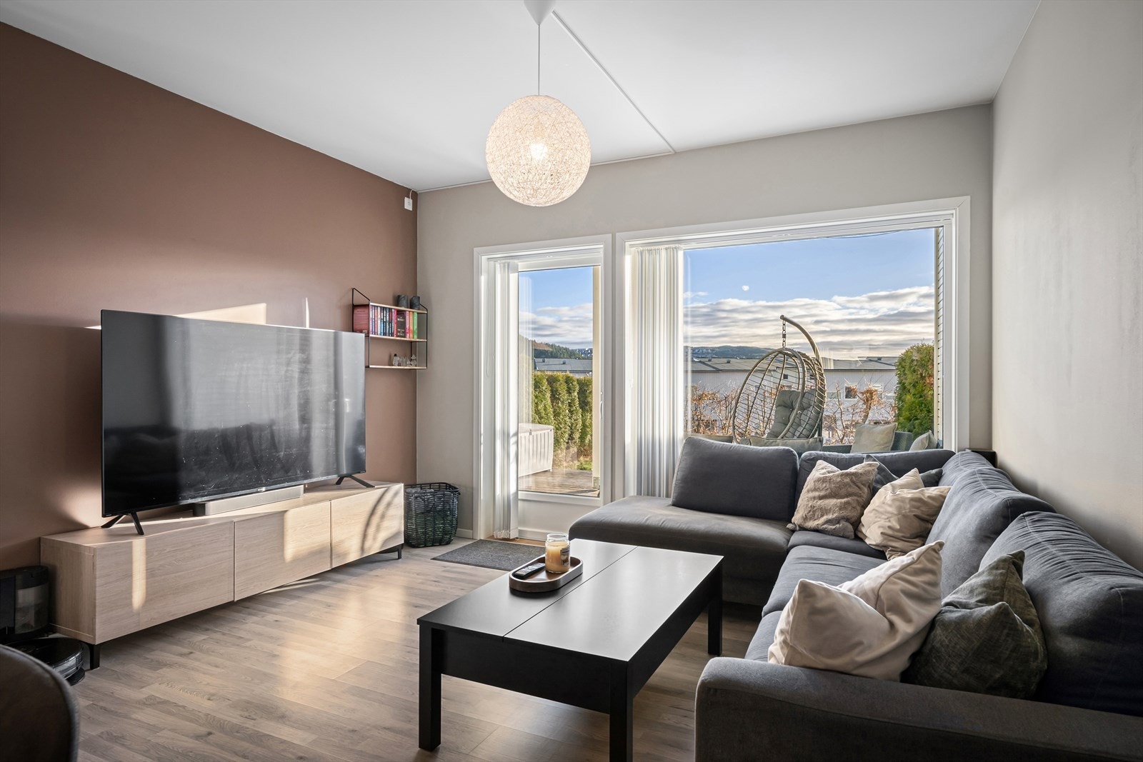 Leilighetens stue fremstår som lys og trivelig med store vindusflater som slipper inn mye naturlig lys som er med på å skape en god romfølelse og atmosfære. Galleribilde