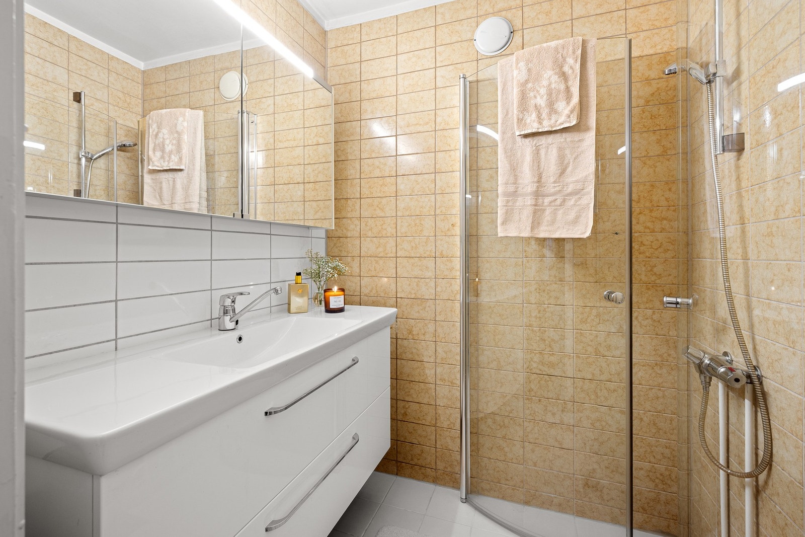 Badet er er innredet med veggmontert servantinnredning med plane fronter. Helstøpt servantplate med 1-greps blandebatteri. Veggmontert speilskap med integrert belysning. Galleribilde