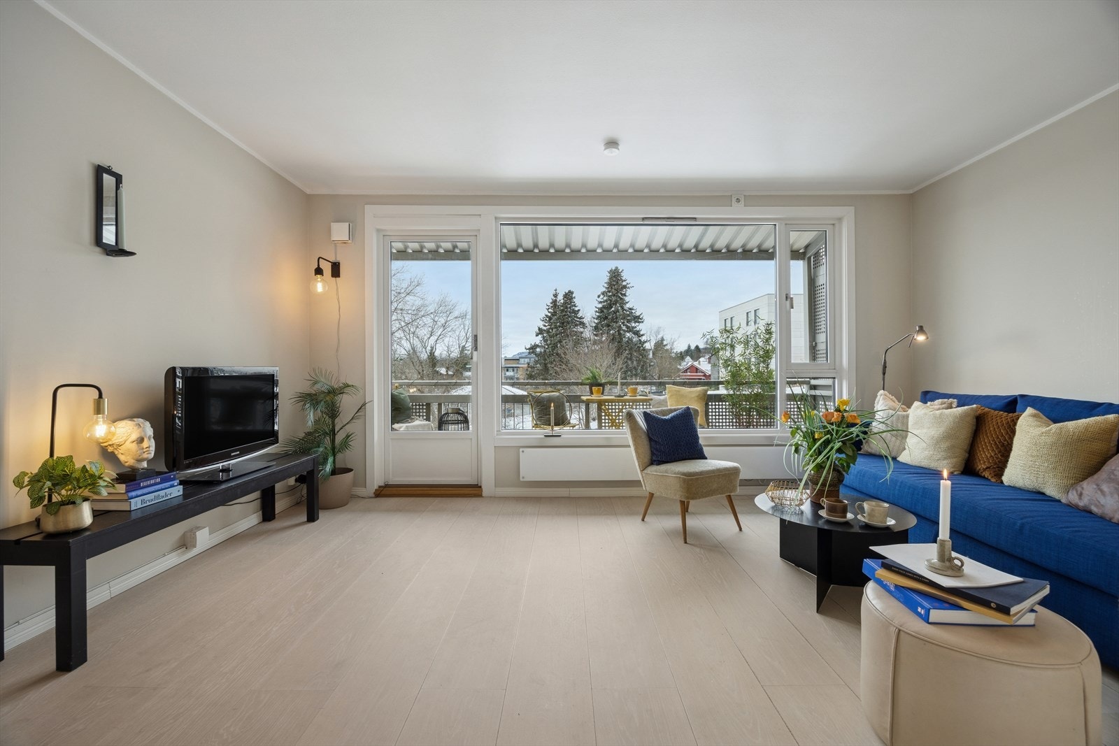 Lys og usjenert stue med pen enstavsparkett på gulv og malte flate vegger. Galleribilde