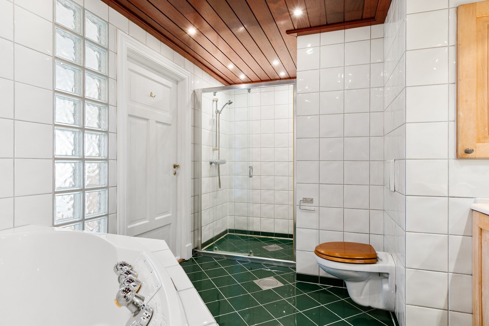 Badet er innredet med vegghengt toalett, dusjnisje og hjørnebadekar Galleribilde