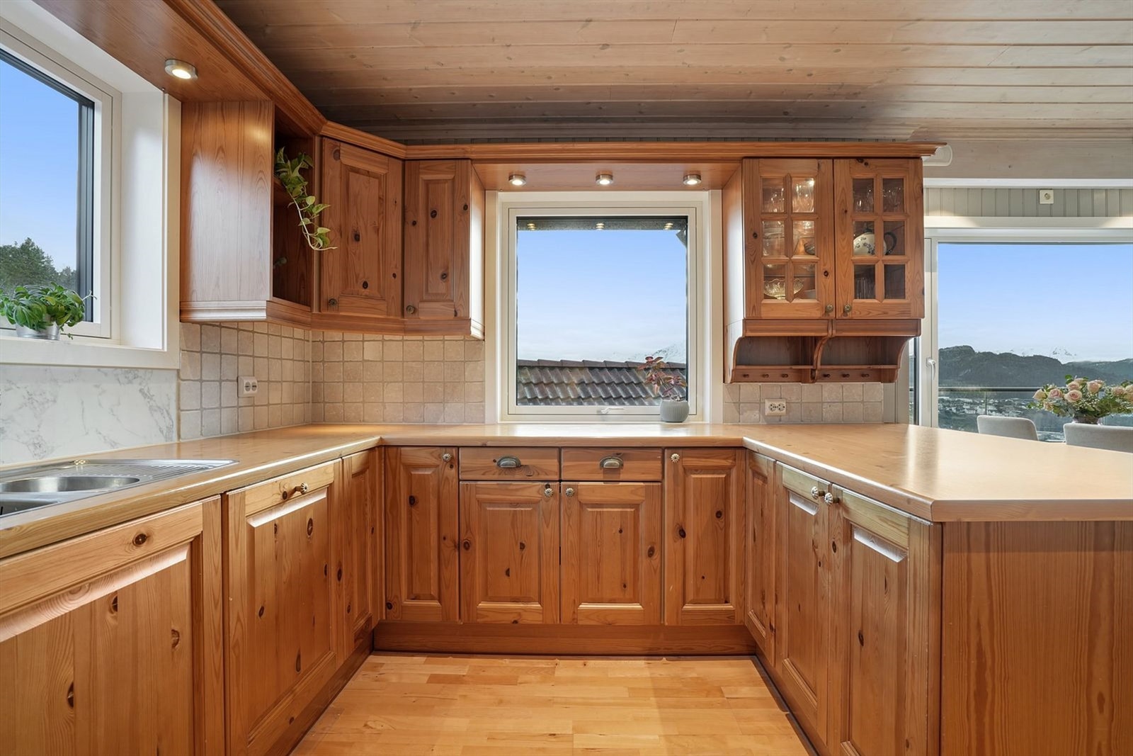 Kjøkkeninnredning med profilerte fronter og kjøkkenhalvøy mot spisedel. Godt med naturlig lysinnslipp fra vinduer. Galleribilde