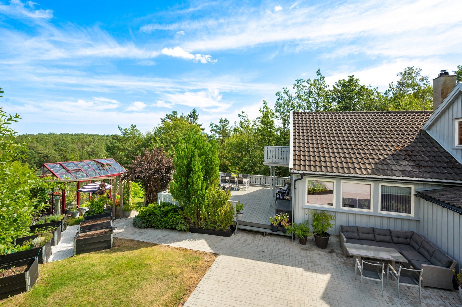 Eiendommen har flere ulike soner med terrasse, hage, platting, drivhus med mer Galleribilde