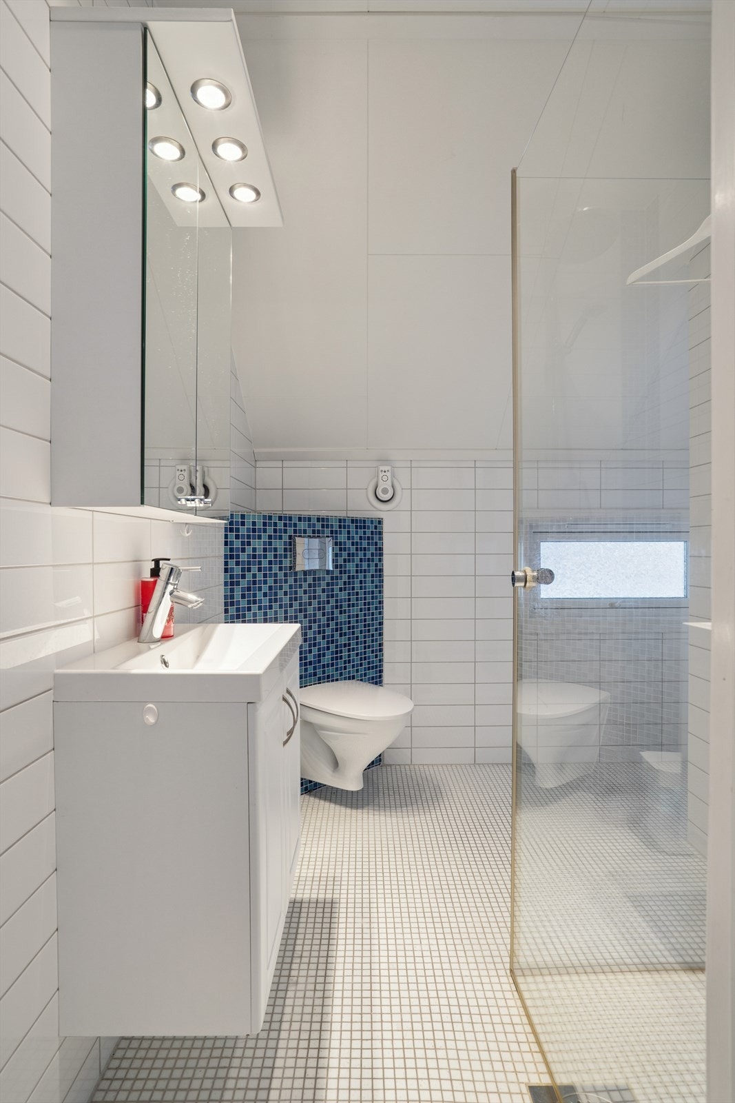 Baderom i 2. etasje er innredet med heldekkene servant og ett- greps blandebatteri, vegghengt speilskap med lys, vegghengt toalett og dusjhjørne med glassdører. Galleribilde