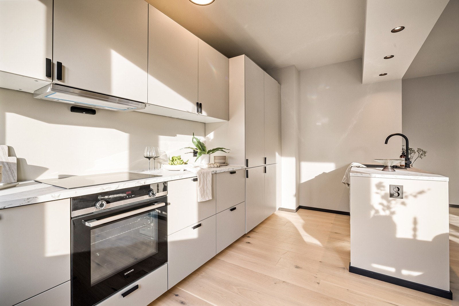 - Lekker kjøkkeninnredning med slette fronter, integrerte hvitevarer og gjennomgående stilrene, sorte detaljer - Galleribilde