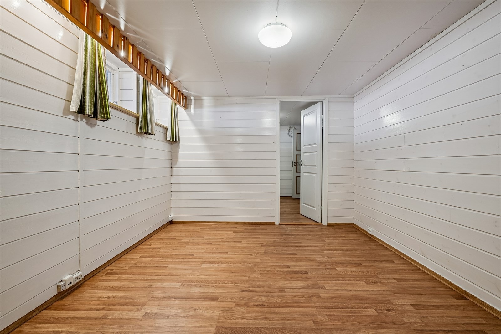 Innredet rom i kjelleren med laminatgulv og panel på veggene. Galleribilde