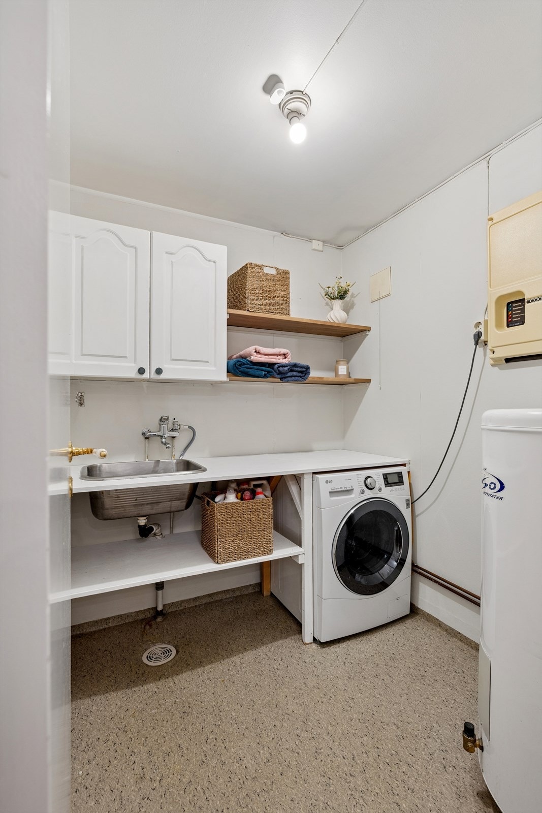 Praktisk vaskerom med belegg på gulv, innredet med servant og vaskemaskin. Galleribilde