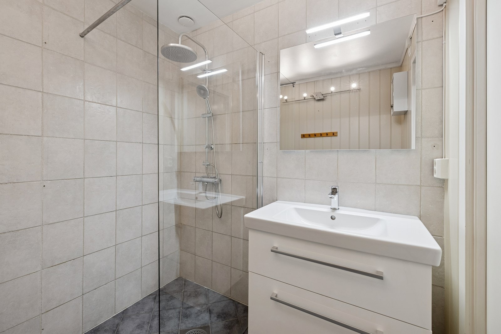 Badet har fliser på vegger og gulv med gulvvarme. Badet er innredet med servant med underskap, speil, dusjvegger. Galleribilde