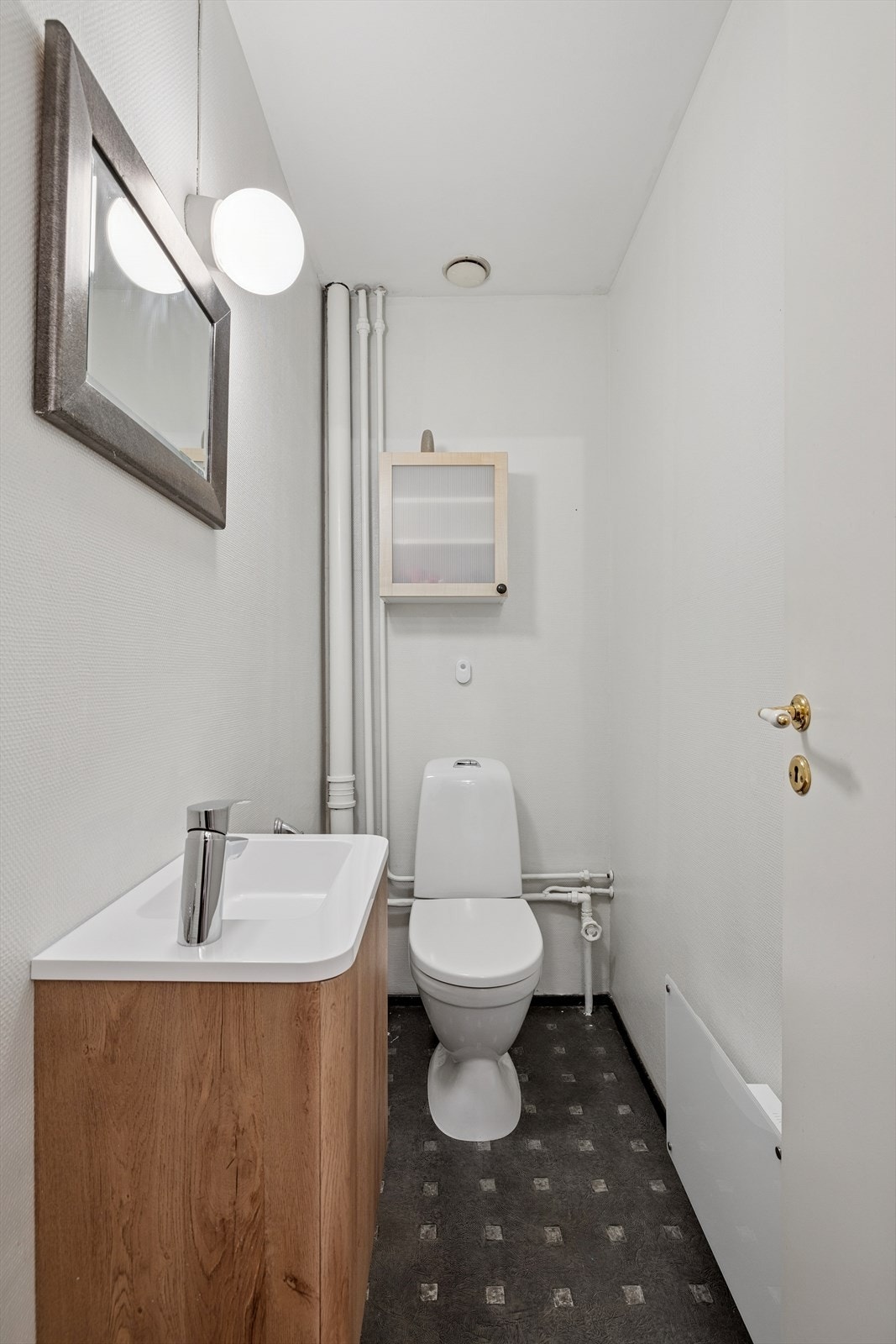 Separat toalettrom med belegg på gulv, innredet med vask, speil og gulvstående toalett. Galleribilde