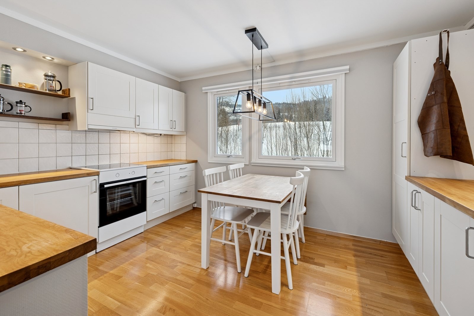 Separat kjøkken med lyse, profilerte fronter og benkeplate med oppvaskkum. Galleribilde