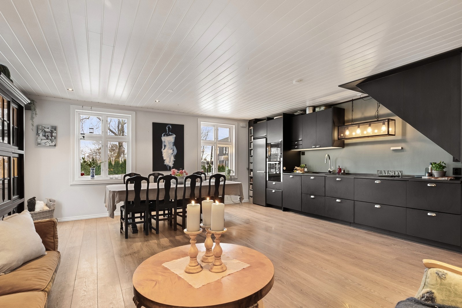 Stuen har en åpen løsning mot kjøkkenet. Det er downlights i himling og planløsningen gir naturlig plass til både sofagruppe og spisebord. Galleribilde