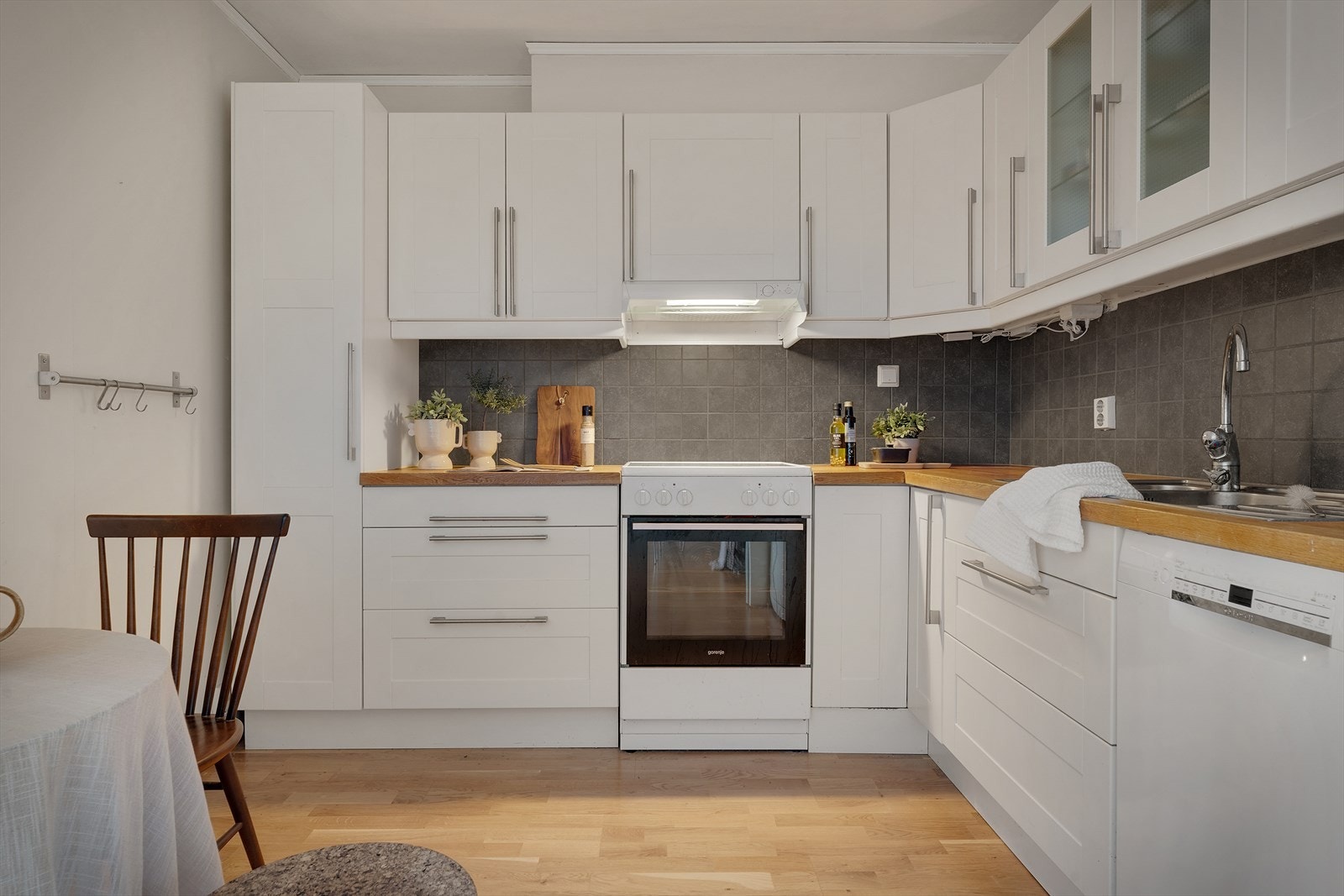 Det er praktisk utstyrt med benkeplate med nedfelt stålvask, samt integrerte hvitevarer som komfyr, oppvaskmaskin og kjøleskap med frysedel Galleribilde