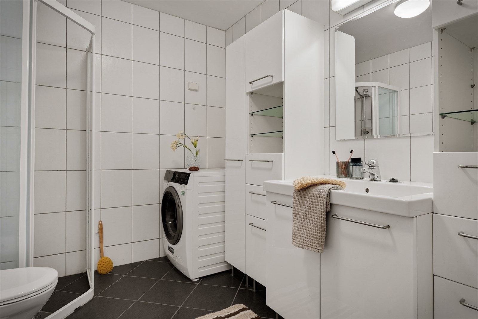 Badet fra 2005 fremstår pent og tidløst, med fliser på både gulv og vegger. Her får du varmekabler i gulvet som gir ekstra komfort, eget dusjhjørne, toalett og mekanisk ventilasjon for et godt inneklima Galleribilde