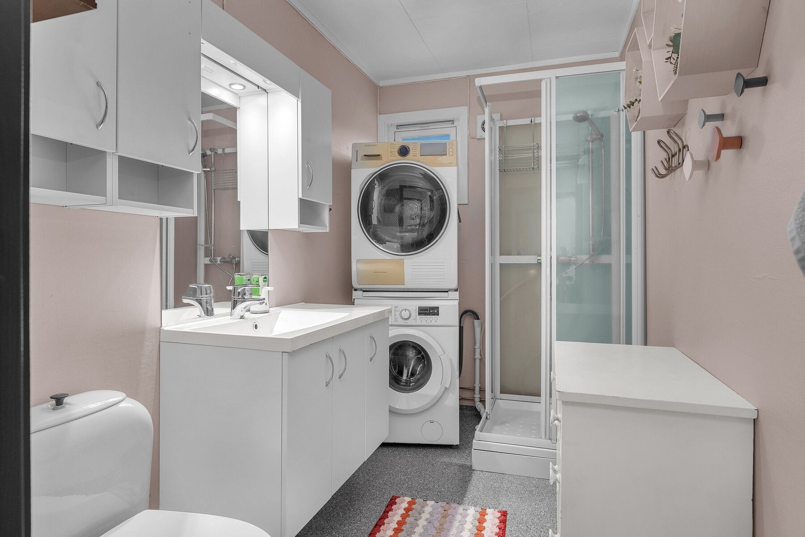 Bad/vaskerom fra byggeår, overflateoppusset i ettertid. Badet er innredet med servant, toalett, dusjkabinett og opplegg for vaskemaskin. Galleribilde