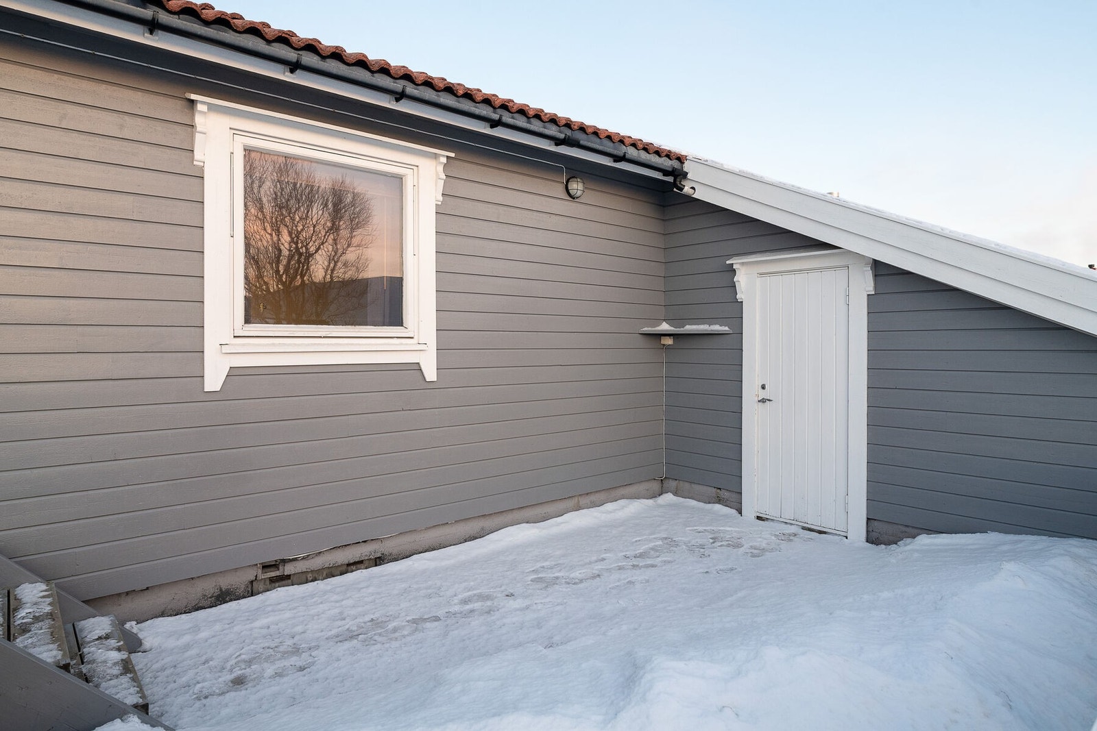 Del av terrasse med adkomst til garasjen, samt hagen som er opparbeidet med plen, trær og beplantning. Galleribilde