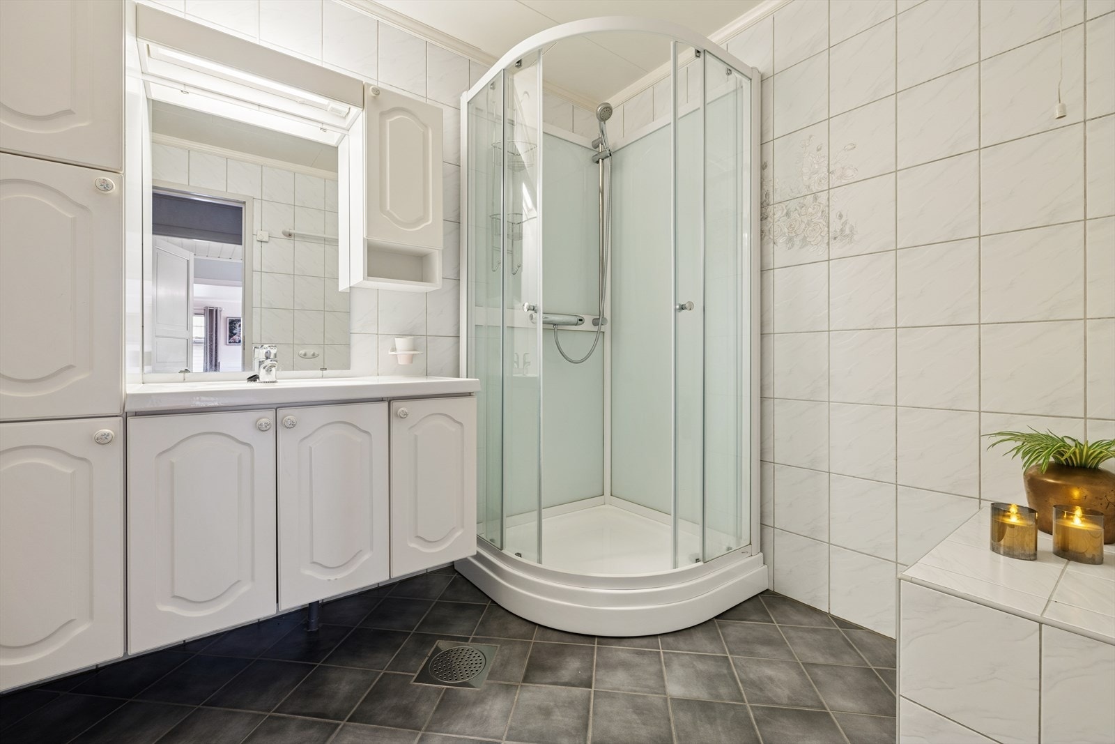 Lyst og pent bad med flislagt gulv og vegger. Det er varmekabler i gulvet som gir en behagelig varme og komfort i rommet. Baderommet er utstyrt med innredning med nedfelt servant og god skapplass. Galleribilde