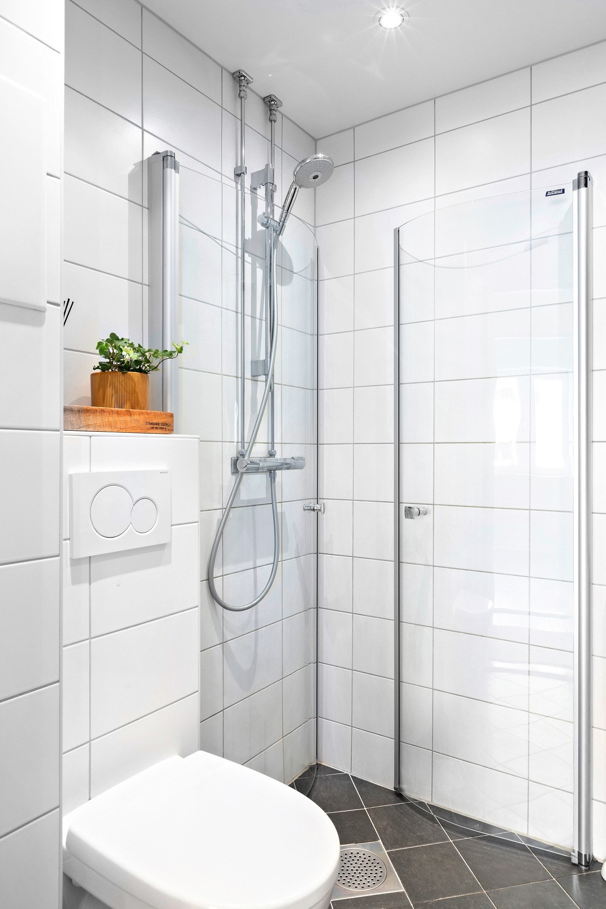 Badet har vegghengt toalett, innsvingbare dusjdører, opplegg for vaskemaskin og downlights i himling. Galleribilde