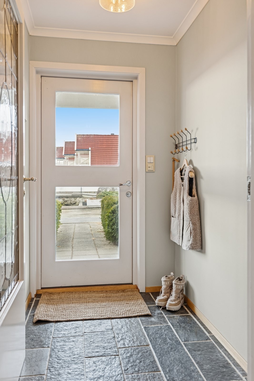 Flislagt entré som ønsker deg velkommen inn, plass til å henge fra seg ytterklær på knaggrekke. Galleribilde