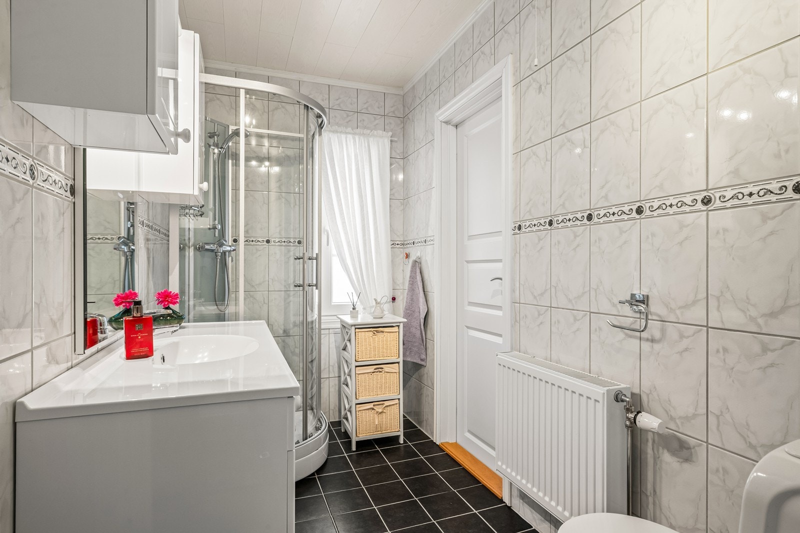 Flislagt bad med dusjkabinett og servant med oppbevaringsplass. Galleribilde