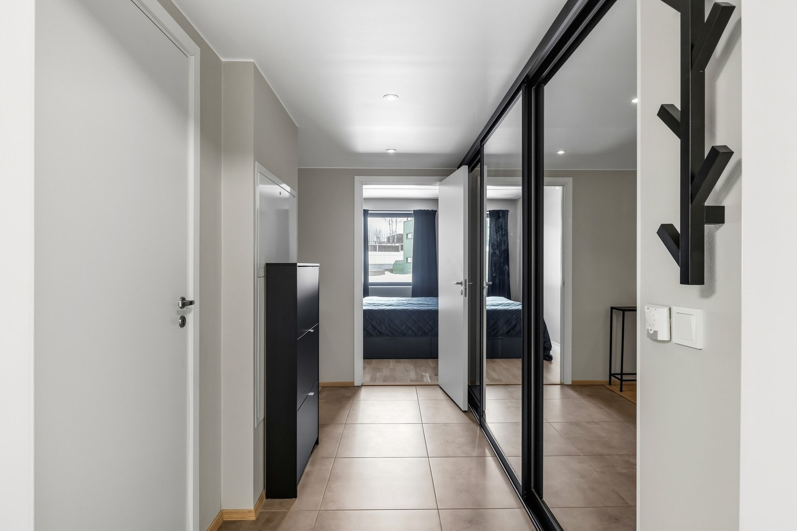 En romslig skyvedørsgarderobe med speilfronter gir rikelig med plass til yttertøy og sko. Galleribilde